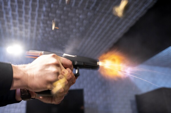 A semi-automatic pistol with a conversion device installed making it fully automatic is fired as four empty shell casings fly out of the weapon, at the Bureau of Alcohol, Tobacco, Firearms, and Explosives (ATF), National Services Center, Thursday, March 2, 2023, in Martinsburg, W.Va. (AP Photo/Alex Brandon, File)